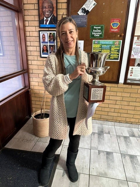 Rand Park P.S. 2026 Mrs. Daniela Schafer, co-ordinator and driving force behind the collection drives at Rand Park Primary, proudly receives the “Kind Cup” floating trophy on behalf of the school.